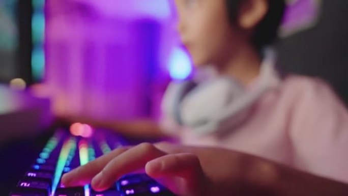 倾斜男孩的手使用RGB键盘在他的电脑上玩视频游戏