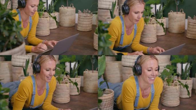 女人使用笔记本电脑，并通过在花店工作的无线蓝牙耳机在线听音乐。植物学家在互联网上搜索植物研究并在工作
