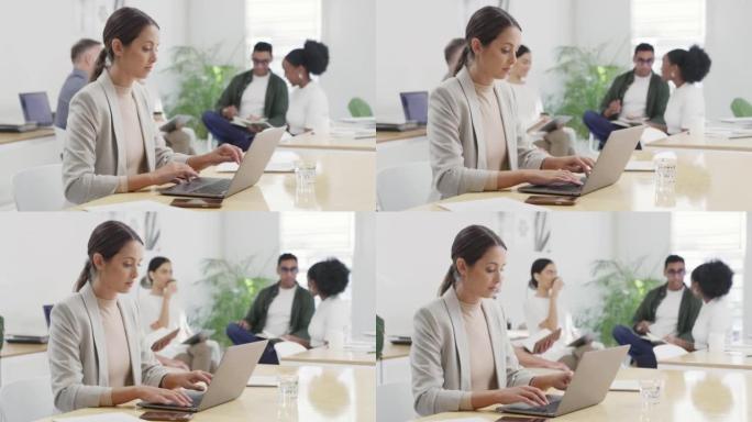 女商人在繁忙的办公室里用笔记本电脑工作，同事在后台。专注的企业家浏览互联网，同时在创业公司的办公桌或