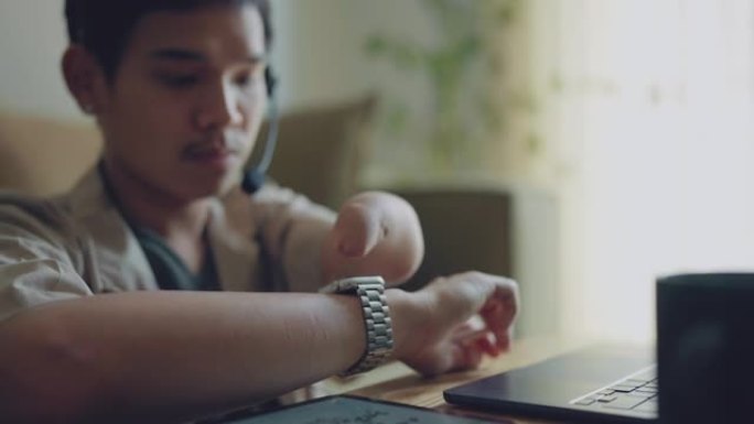 亚洲男子残疾畸形的手臂在家里工作。