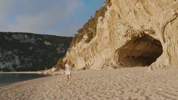 意大利撒丁岛海滩上散步的女人的SLO MO视图。