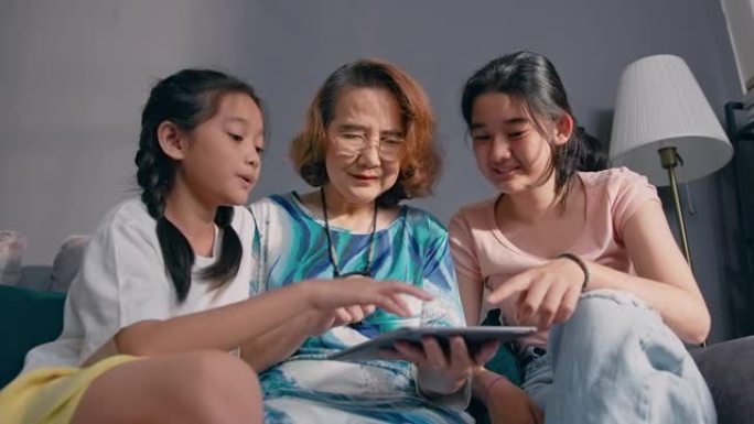 亚洲孙女在家教祖母在数字平板电脑上画画。