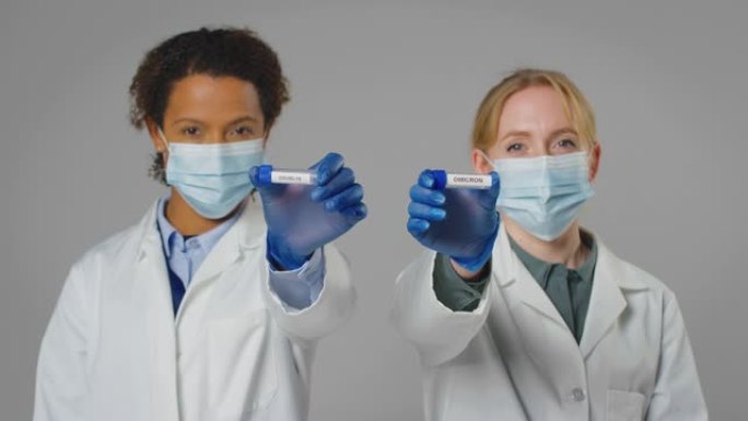 工作室拍摄的实验室研究人员戴着口罩，手里拿着标有欧米克隆和Covid-19的试管