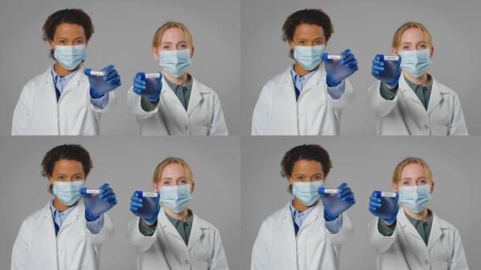 工作室拍摄的实验室研究人员戴着口罩，手里拿着标有欧米克隆和Covid-19的试管