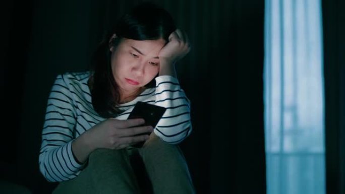 孤独的女人坐在床上使用智能手机