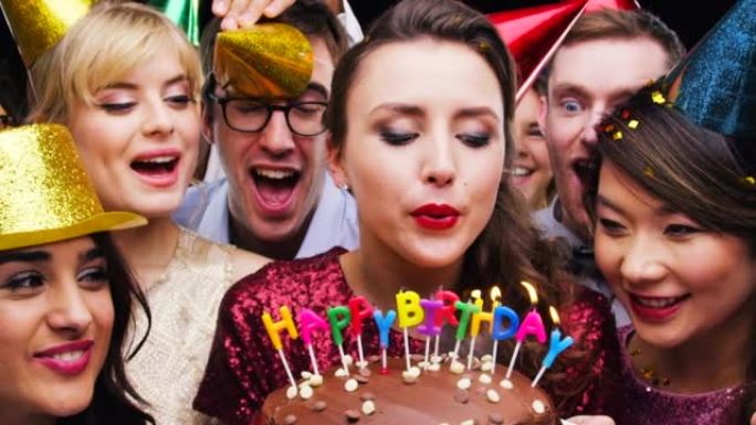 一群朋友在工作室背景下在生日蛋糕上吹蜡烛的4k视频片段