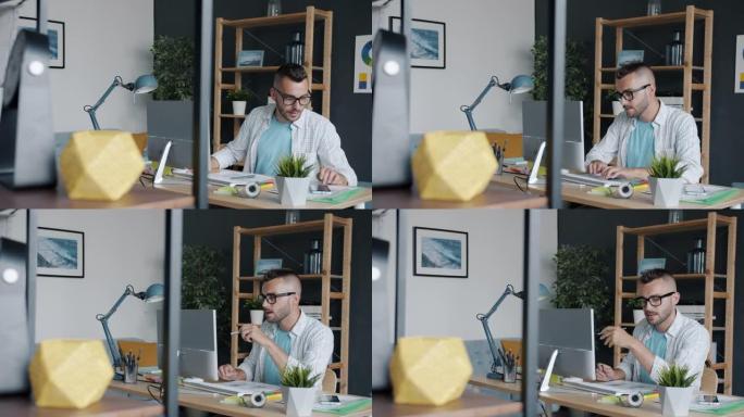 智能手机应用程序设计师在办公室使用设备书写和电脑打字的慢动作肖像