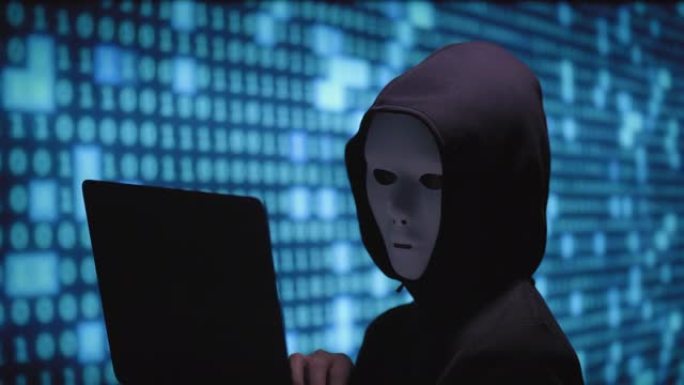 匿名计算机黑客在屏幕上使用电话和二进制代码