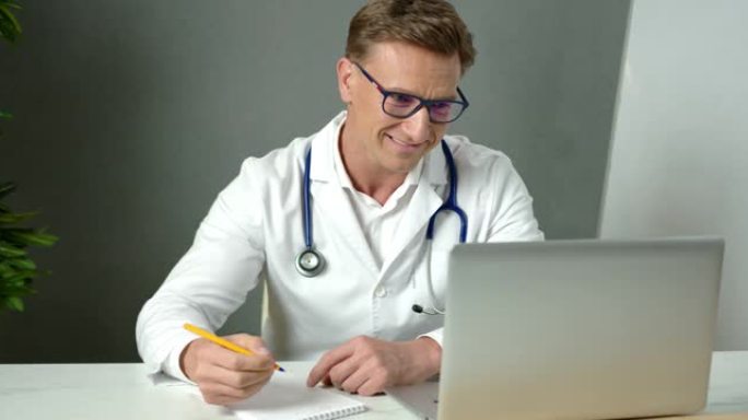 英俊的男医生在视频会议上与远程病人一起工作，使用在线虚拟聊天。远程会诊医疗专业微笑远程医疗计算机应用