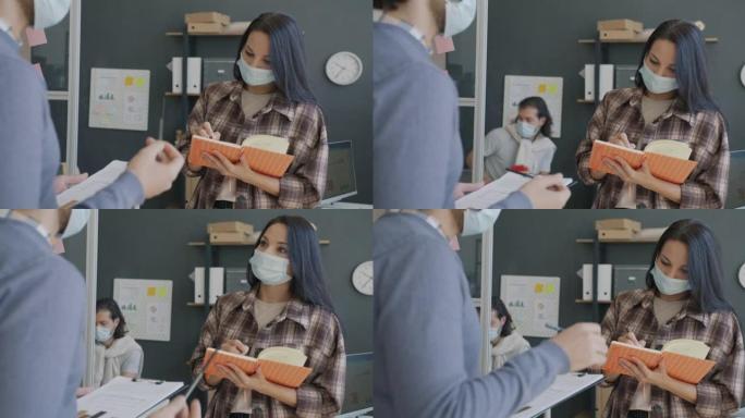 戴着医用口罩的年轻女子得到老板的命令，在办公室做笔记