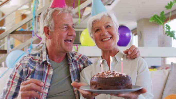 白人高级夫妇拿着蛋糕在家庆祝生日的肖像