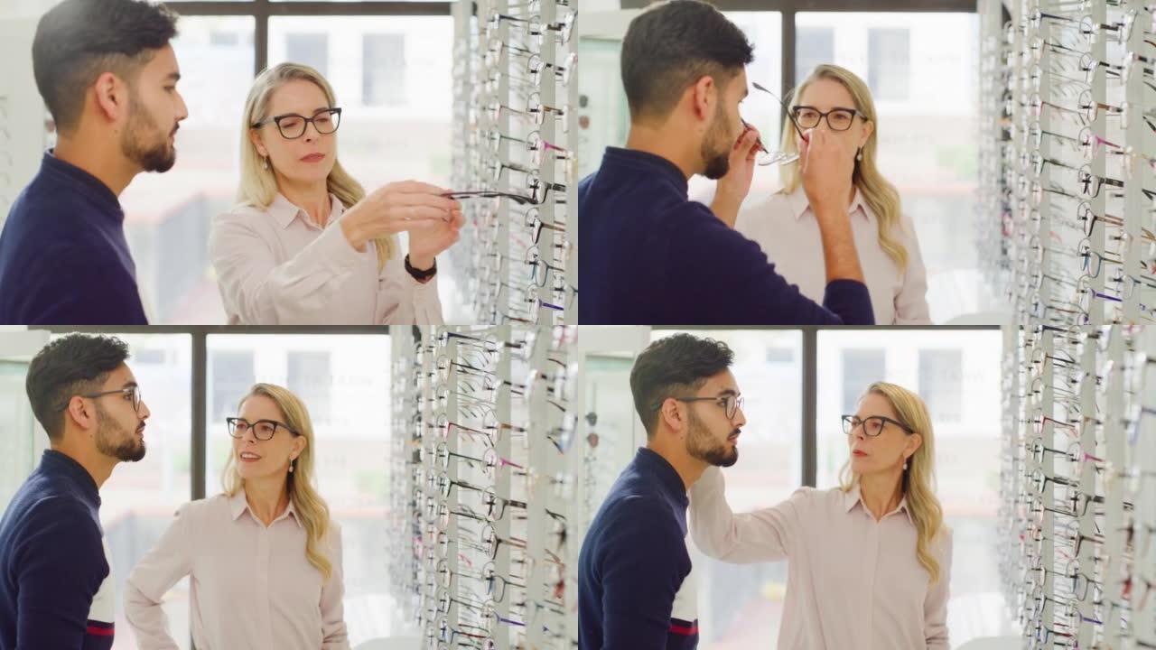 女性配镜师或验光师帮助顾客选择她商店货架上的眼镜。友好的成熟女人和店主在她的眼镜店帮助男人选择和试戴