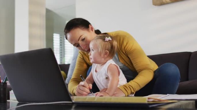 白人母亲在家工作时抱着婴儿做笔记