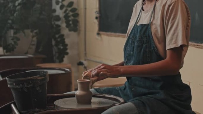 在陶轮上制作小花瓶的女人