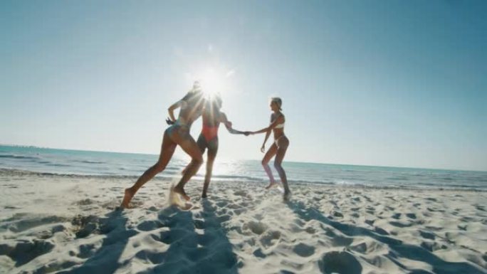 穿着泳衣的年轻多民族女友的慢动作在阳光明媚的日子里，一起在海边享受暑假。