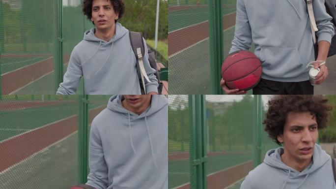 带球的年轻人在室外篮球场旁散步