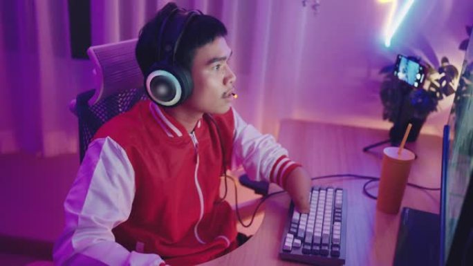 自信的残疾亚洲男性职业玩家在家玩在线电脑游戏。