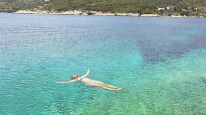 漂浮在亚得里亚海某个海湾的绿松石水上的空中女人