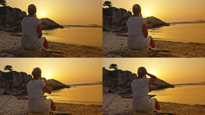 一个金发女孩坐在沙滩上的景色，撒丁岛。