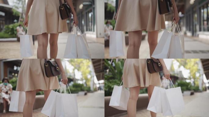 女人的腿带着购物袋走在街上