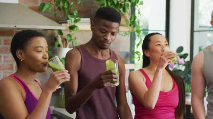 一群不同的年轻人在家里一起喝绿色健康冰沙