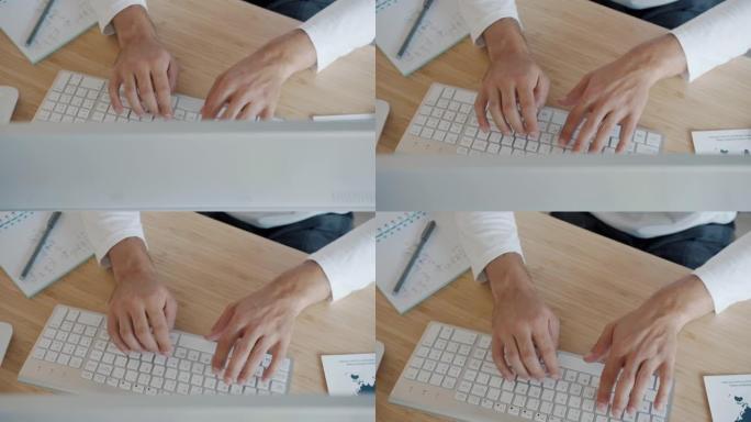 在办公桌室内用电脑键盘打字的男性手的高角度视图特写