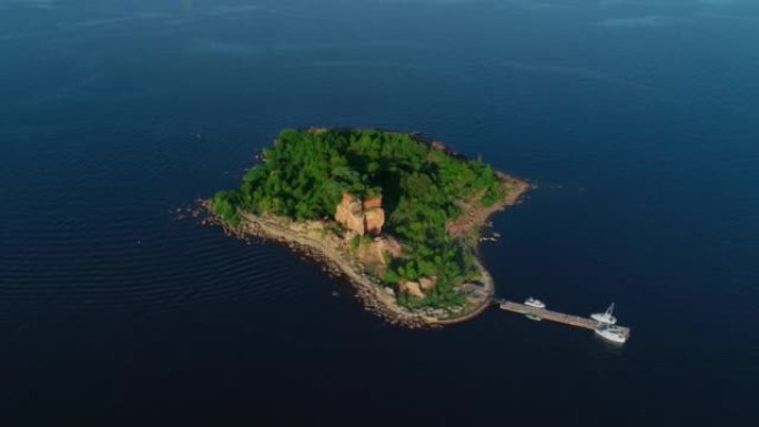 一架无人驾驶飞机在阳光明媚的日子里，在壮丽的岛屿上鸟瞰，森林在海洋或海洋中，小船在码头上