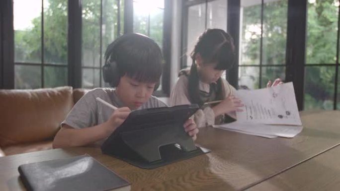 男孩和女孩正坐在家里专心在线学习，他记下了他所学到的知识。通过笔记本电脑，人们因为covid 19而