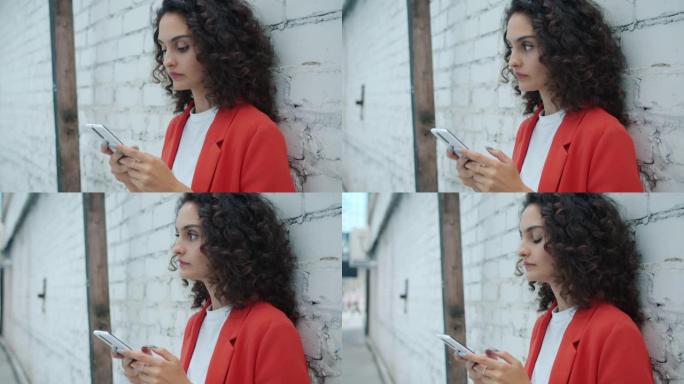 使用智能手机专注于站在户外的在线内容的沉思女孩的肖像