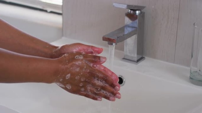 非裔美国妇女在家里的浴室水槽里洗手的特写