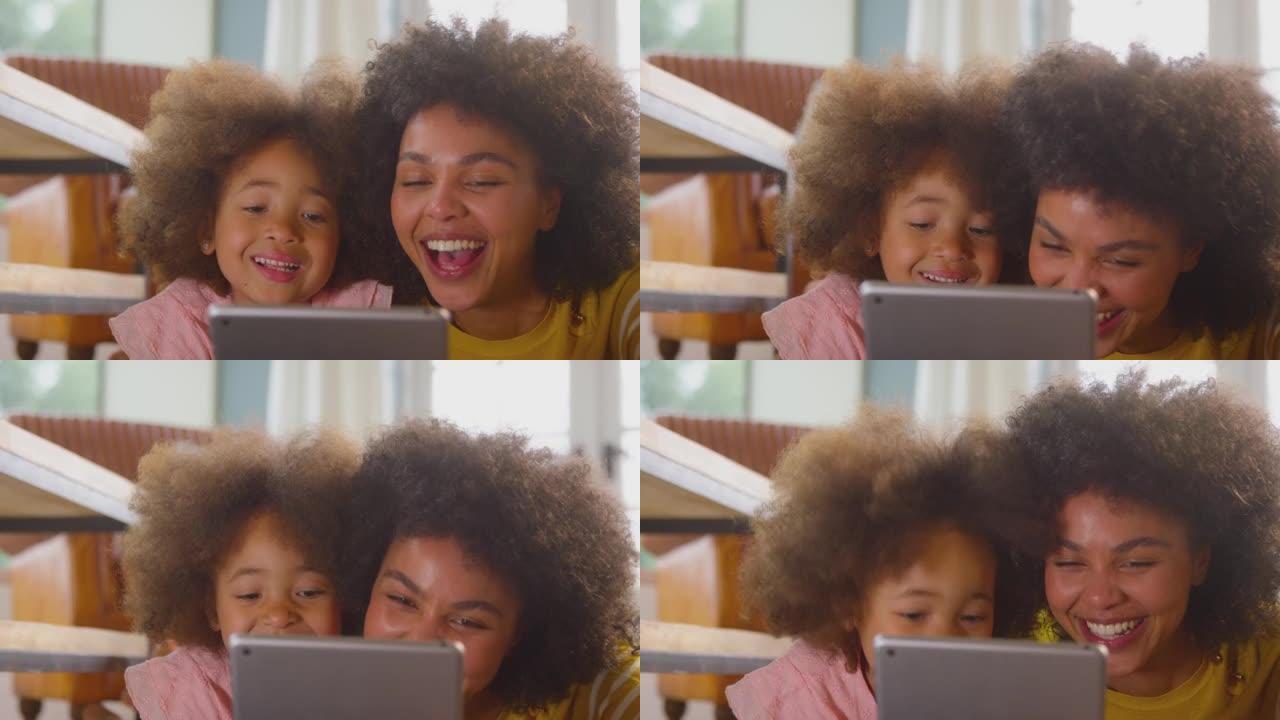 母女俩在家一起躺在数字平板电脑上的地板上看得很开心 -- 慢动作拍摄