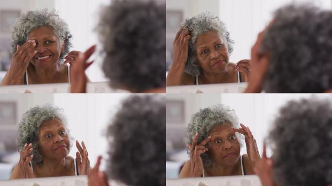 资深非裔美国妇女在家照镜子时摸着头发