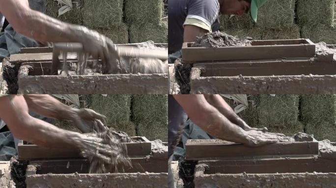 制造土坯砖 (泥砖) 作为建筑材料的人，通常采用由泥土和有机材料制成的晒干砖的形式。特写。