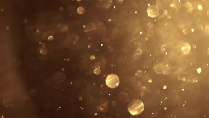 金尘颗粒在空中飞舞。闪烁发光的金色散景背景。