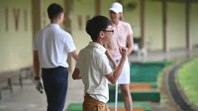 亚洲中国活跃的高级祖父高尔夫球手向孙子击掌，以庆祝在高尔夫练习场首次开球