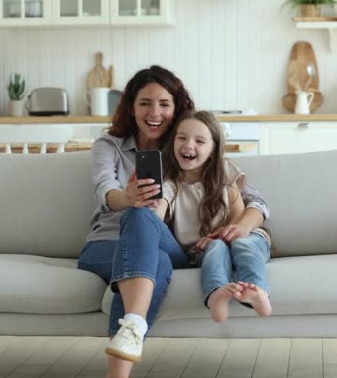 妈妈，她的小女儿盯着智能手机屏幕，享受视频会议