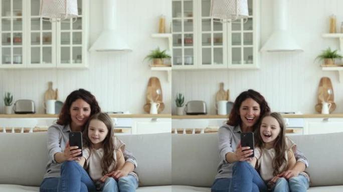 妈妈，她的小女儿盯着智能手机屏幕，享受视频会议