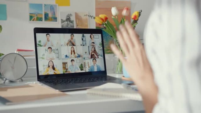 年轻的亚洲女性员工在家里用笔记本电脑在线与不同的多种族同事进行视频通话。