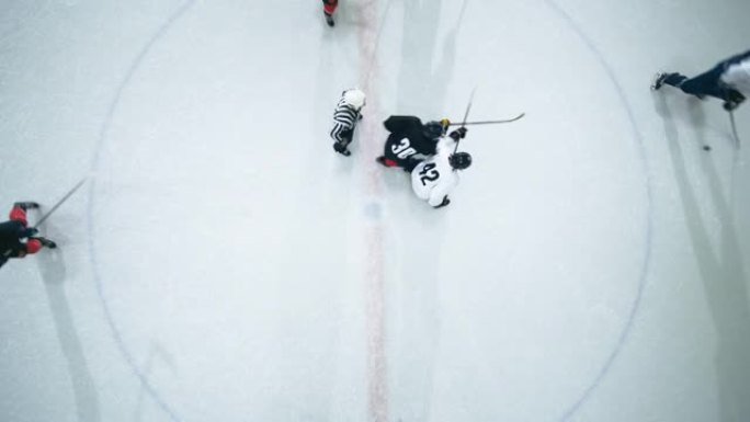 俯视图冰球场竞技场比赛开始: 两名球员对峙，准备棍棒，裁判放下冰球，运动员为之奋斗。激烈的比赛范围。