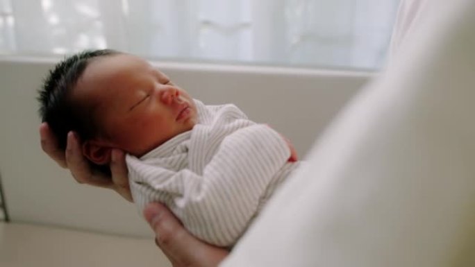 关闭父亲的手在家里的托儿所里抱着新生的男婴。陪产假