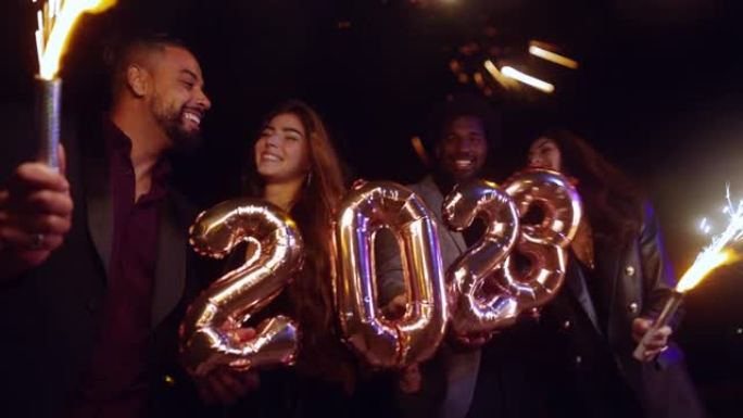 一群朋友庆祝新年拿着2023气球和烟火