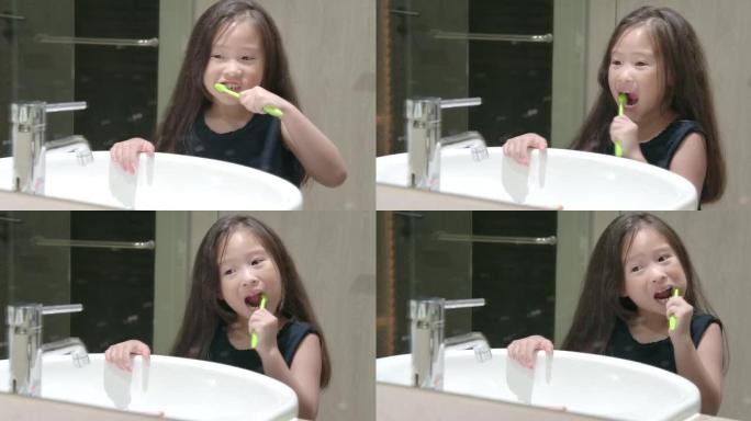 可爱的小女孩在浴室的镜子前刷牙