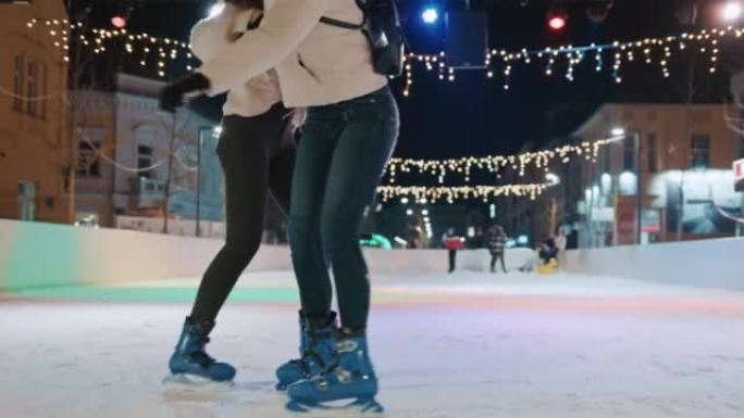 两个美丽的年轻女子晚上在溜冰场上滑冰