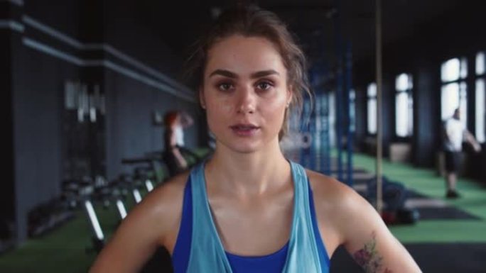 放大肖像，严肃年轻漂亮的女运动员看着相机，在健身俱乐部剧烈锻炼后累了。