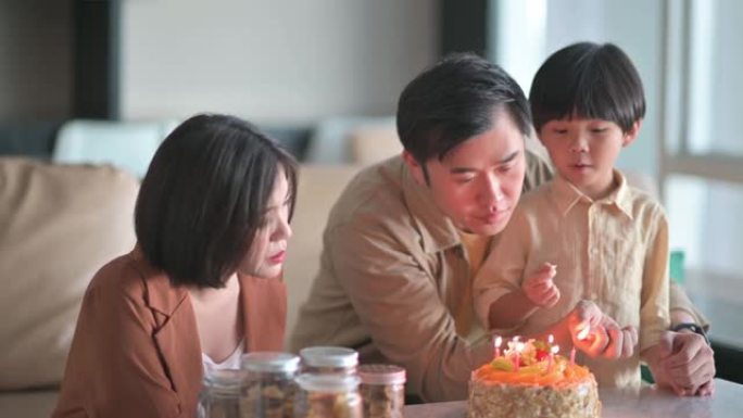 亚洲华裔父亲用打火机点燃生日蜡烛准备在客厅为儿子唱生日歌庆祝生日