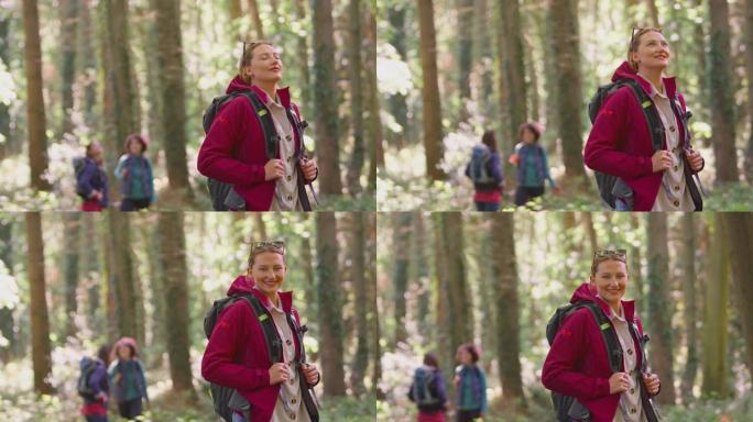 女人的肖像深呼吸，闭上眼睛享受和平，一群女性朋友在假日徒步穿越树林-慢动作拍摄