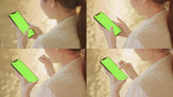 特写女人手在夜间使用带色度键绿屏的智能手机