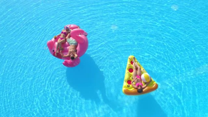 空中: 三个朋友在无忧无虑的暑假期间在五颜六色的漂浮物上放松