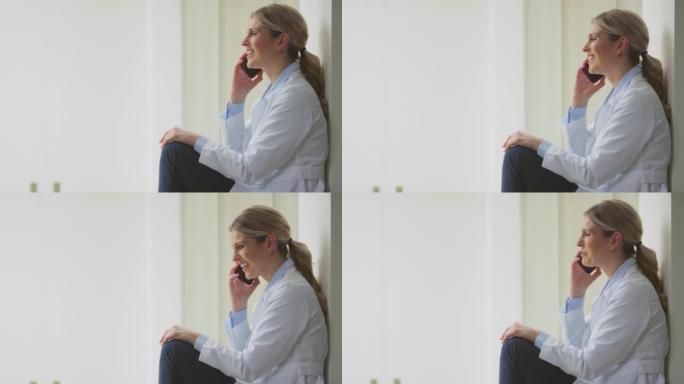 穿着白大褂的女医生坐在医院走廊上聊天手机-慢动作拍摄