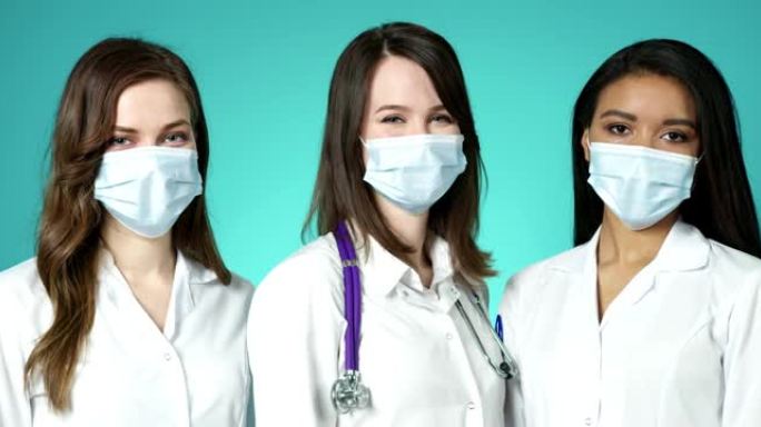 美丽的年轻女性医生在室内戴着医用口罩。国际集团自信的专业女医务人员摆白大褂慢动作新型冠状病毒肺炎保护